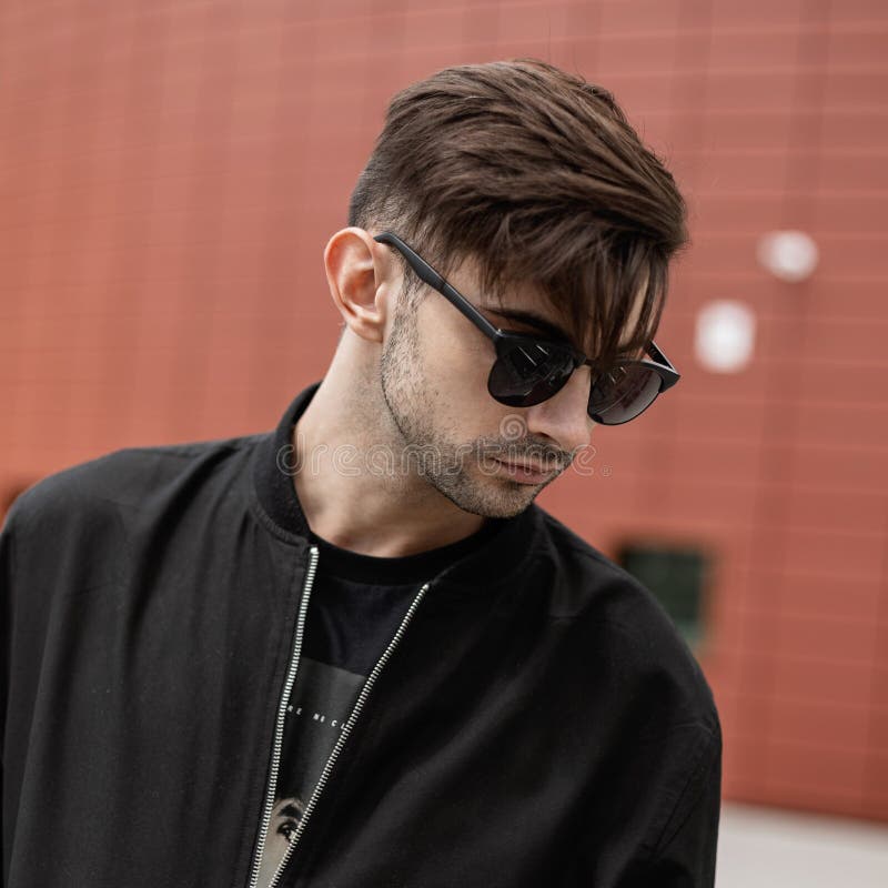 Handsome Young Man Hipster with a Fashionable Hairstyle in Stylish  Sunglasses in a Black Trendy Jacket in the City Stock Photo - Image of  adult, american: 154111702