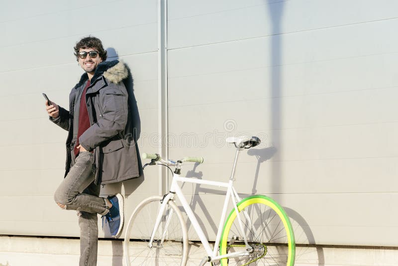 Handsome young man with mobile phone and fixed gear bicycle. Horizontal, male.
