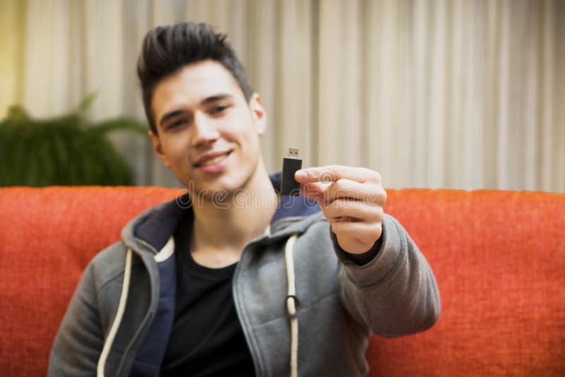 Handsome young man showing USB key in his hand