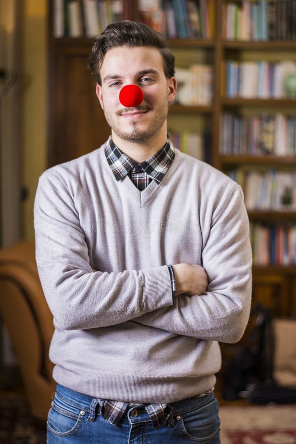 Handsome young man smiling with red clown nose