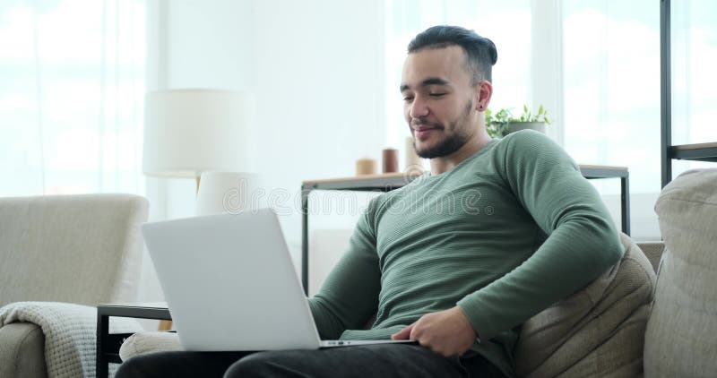 Handsome young man video conferencing using laptop on sofa stock video
