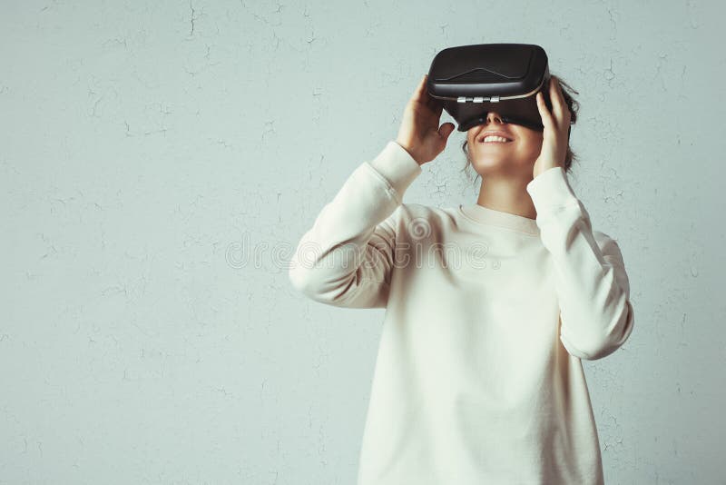 Handsome young woman wearing virtual headset. Smiling hipster using VR glasses. Blank sweater stock image Handsome young woman wearing virtual headset. Smiling hipster using VR glasses. Blank sweater stock image