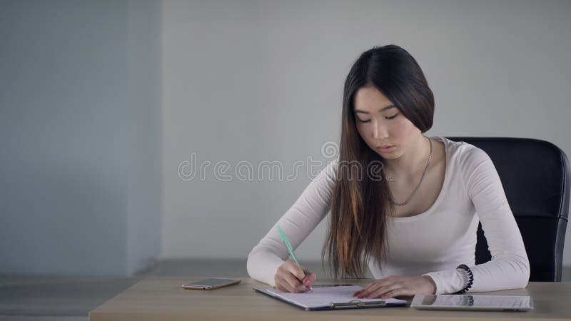 Handstilpenna för ung kvinna på pappers- sammanträde på tabellen inomhus