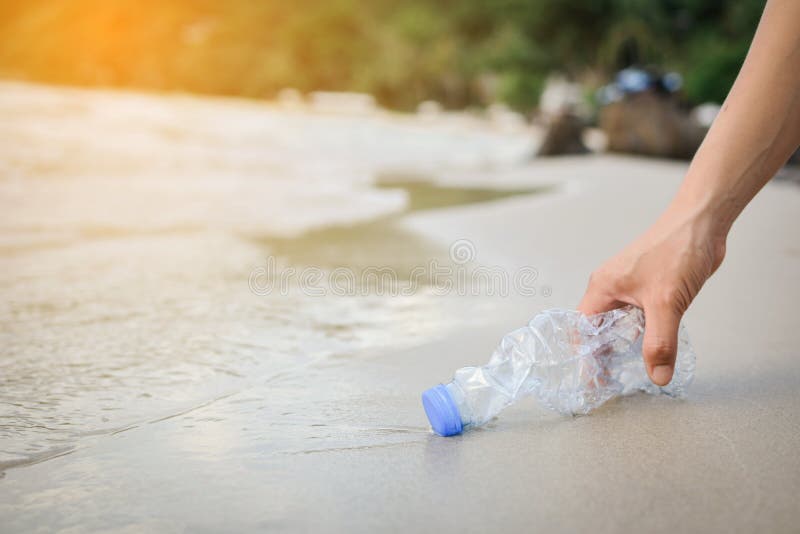 Handvrouw die het plastic fles schoonmaken op het strand opnemen royalty-vrije stock afbeeldingen Handvrouw die het plastic fles schoonmaken op het strand opnemen royalty-vrije stock afbeeldingen