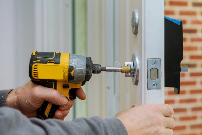 Handyman Using a Drill To Installing Lock in Door in a House Stock