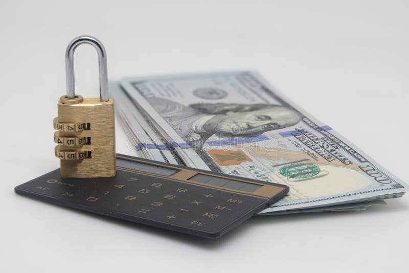Padlock on a hundred dollar bill and a calculator on a white background, saving capital and savings, focus stacking. Padlock on a hundred dollar bill and a calculator on a white background, saving capital and savings, focus stacking