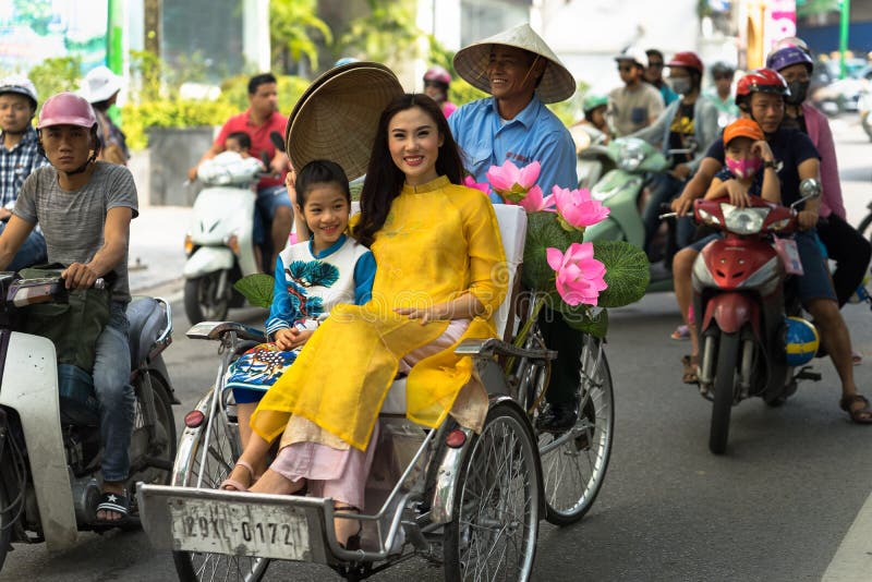 Hanoi Vietnam - Oktober 16, 2016: Den vietnamesiska flickan bär den traditionella långa klänningen Ao Dai som passerar Cyclo pedi