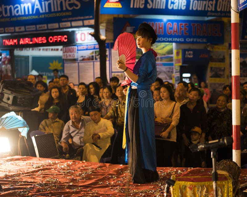 Hanoi, Vietname - 2 de novembro de 2014: O dançarino com fã vermelho e roupa tradicional velha executa a dança antiga da música f fotografia de stock royalty free Hanoi, Vietname - 2 de novembro de 2014: O dançarino com fã vermelho e roupa tradicional velha executa a dança antiga da música f fotografia de stock royalty free
