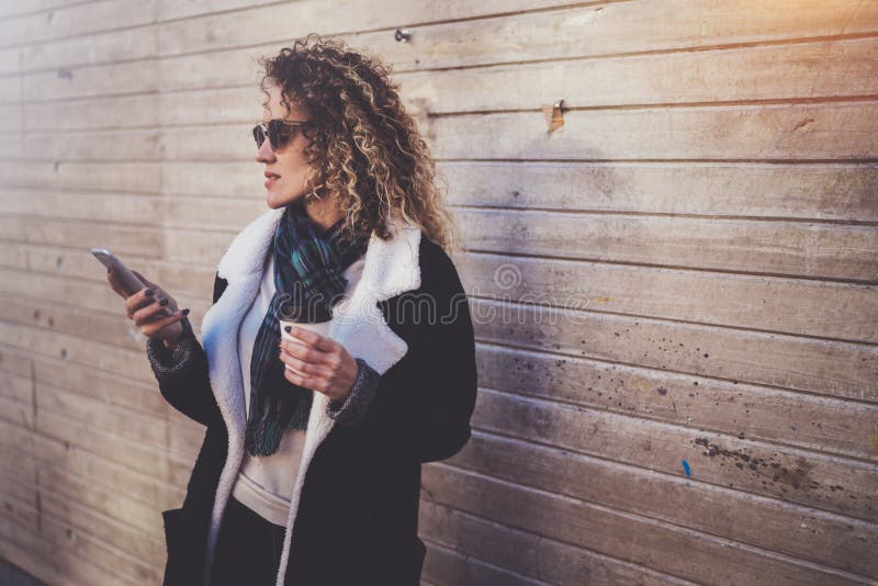 Hansome young woman hipster searching information in mobile network by smart phone, during walking in european city stock image Hansome young woman hipster searching information in mobile network by smart phone, during walking in european city stock image