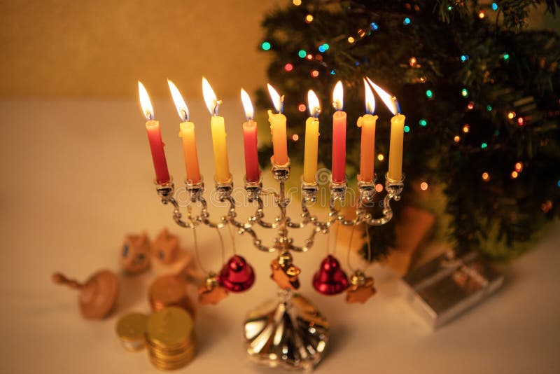 Hanukkah and Christmas together. Hanukkah menorah decorated with bells and stars of David with candles burning aside Christmas tree, . Concept of two holidays royalty free stock images Hanukkah and Christmas together. Hanukkah menorah decorated with bells and stars of David with candles burning aside Christmas tree, . Concept of two holidays royalty free stock images