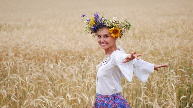 Happiness, nature, summer holidays, vacation and people concept - smiling young woman in wreath of flowers walking along stock video Happiness, nature, summer holidays, vacation and people concept - smiling young woman in wreath of flowers walking along stock video