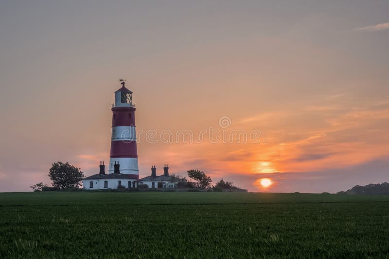Happisburghs fyr och den nedgående solen arkivbild