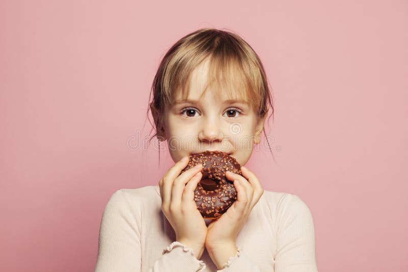 Happy adorable little girl holding chocolate donut. Happy Child on pink background royalty free stock image Happy adorable little girl holding chocolate donut. Happy Child on pink background royalty free stock image