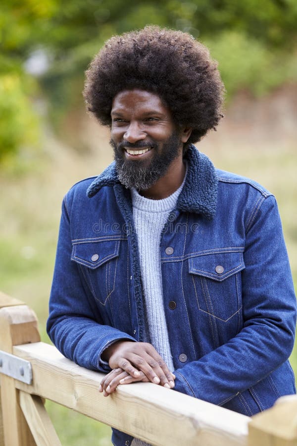 Happy adult black man leaning on a wooden fance in the countryside smiling, close up royalty free stock images Happy adult black man leaning on a wooden fance in the countryside smiling, close up royalty free stock images