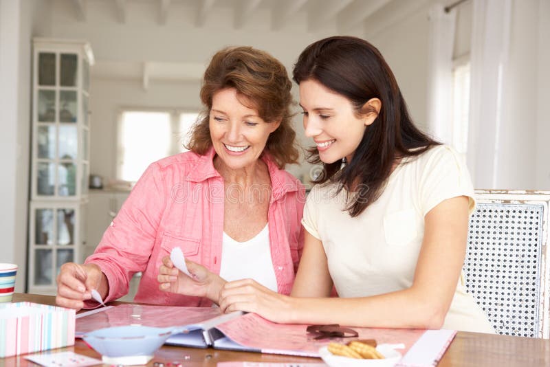 Happy adult mother and daughter scrapbooking together smiling