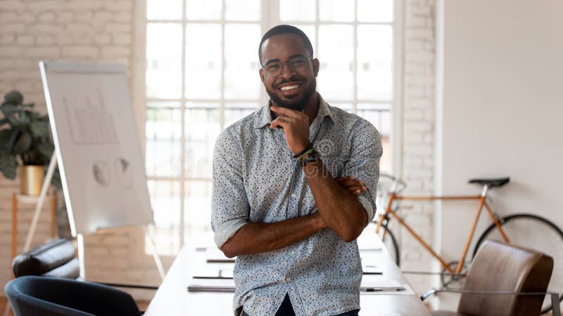 Happy african american businessman standing in modern office, business portrait