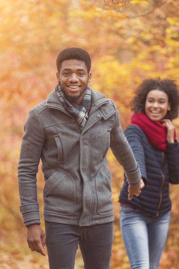Happy african-american couple enjoying walk, woman following boyfriend royalty free stock photography Happy african-american couple enjoying walk, woman following boyfriend royalty free stock photography