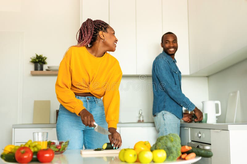 Happy African American Couple Preparing Healthy Food Spending Time In Kitchen Together Talking 