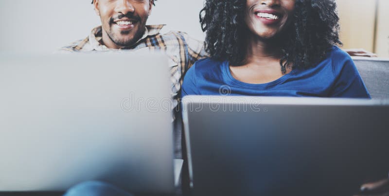 Happy african american couple relaxing together on the couch.Young black man and his girlfriend using laptop at home in stock image Happy african american couple relaxing together on the couch.Young black man and his girlfriend using laptop at home in stock image