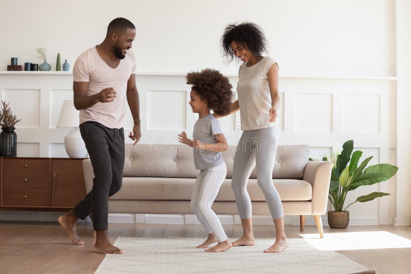Happy african american family having fun, dancing at home. stock image