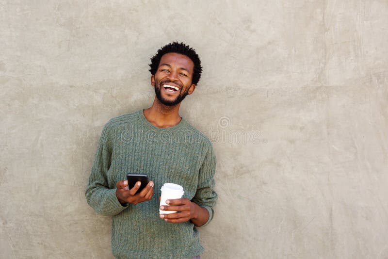 Happy african american man holding smart phone and coffee stock photography Happy african american man holding smart phone and coffee stock photography