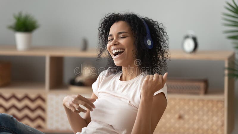 Happy African American woman in headphones listening to music, singing