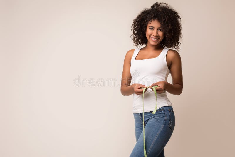 Happy african-american woman measuring waist with tape