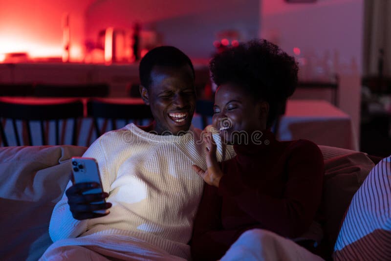 Happy african couple man and woman enjoy video call with friends or family via smartphone at home