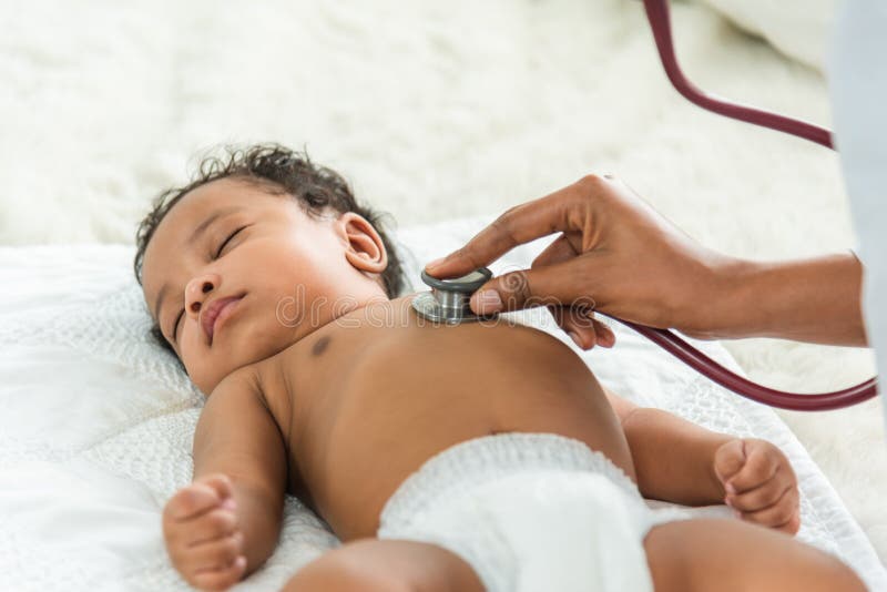 Happy african female doctor examining baby boy with female nurse on background