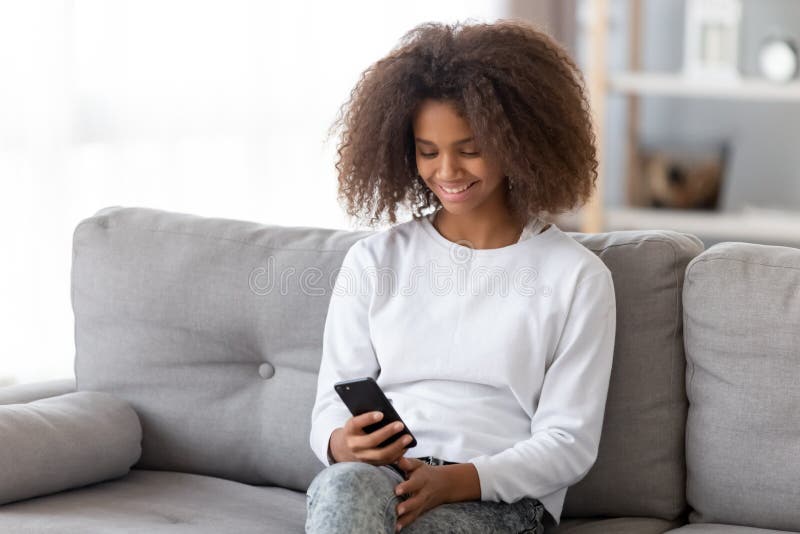 Happy african teen girl holding smartphone using apps at home royalty free stock photo Happy african teen girl holding smartphone using apps at home royalty free stock photo