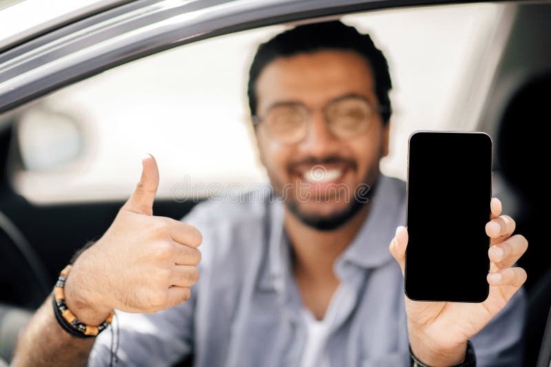 Happy arab man driver holding cellphone with empty screen, mockup stock images