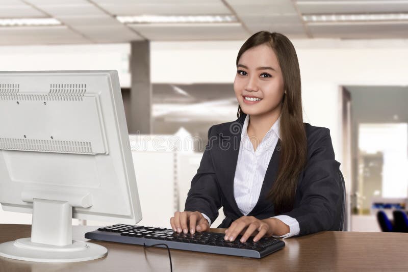 Happy asian business woman working with a desktop computer