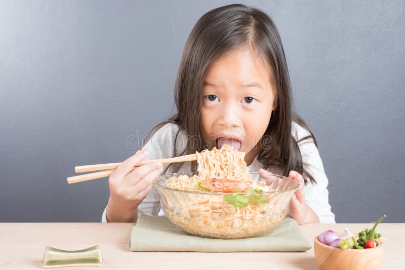 Happy Asian child eating delicious noodle