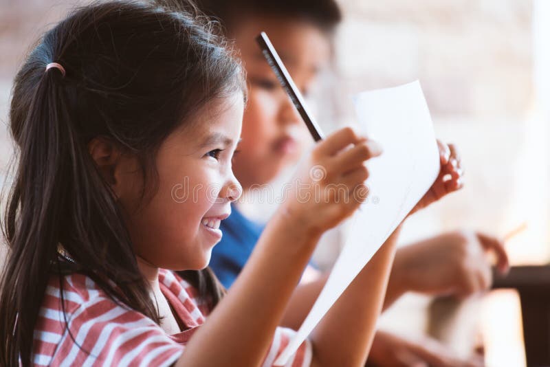 Happy asian child girl holding paper after drawing and painting with her friend with fun