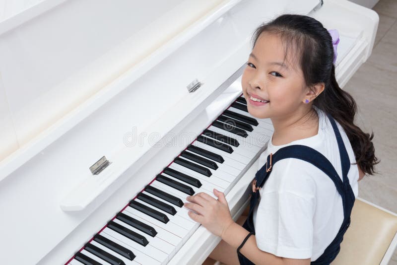 Happy Asian Chinese Little Girl Playing Classical Piano at Home Stock