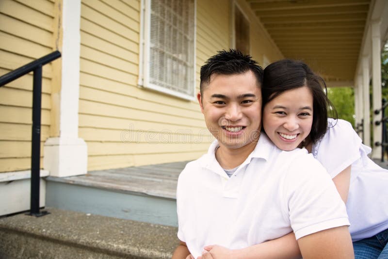 A happy asian couple sitting on the porch in front of their house stock ima...