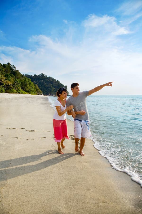 Happy asian couple walking along the beach