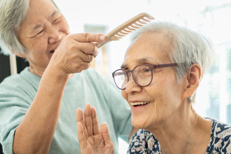 Happy asian elderly women,female senior combing hair to friend senior woman in nursing home,smiling old people or sister care