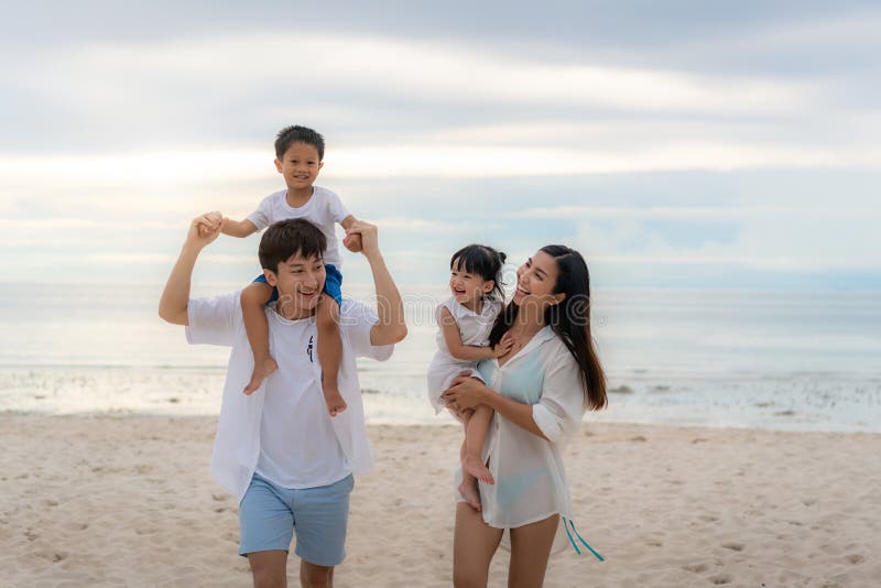 Happy Asian family holidays during joyful father, mother, son and daughter walking together along summer sunset sea. Happy family stock photo Happy Asian family holidays during joyful father, mother, son and daughter walking together along summer sunset sea. Happy family stock photo