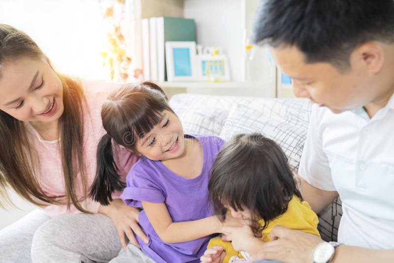 Happy Asian family playing together at sofa in home living room