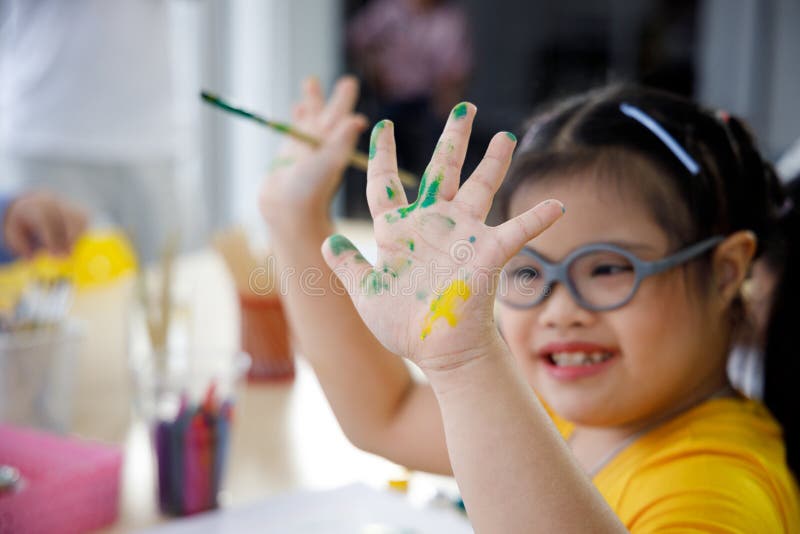 Asian girl with Down`s syndrome painting her hand.