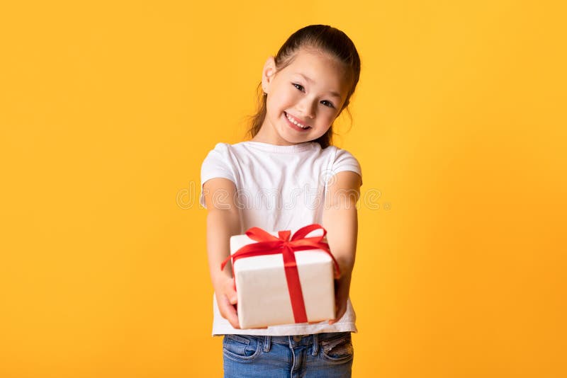 Happy asian girl giving you gift box at studio