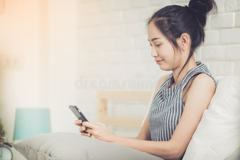 Happy asian girl reading smart phone with smile face on bed . royalty free stock photography Happy asian girl reading smart phone with smile face on bed . royalty free stock photography