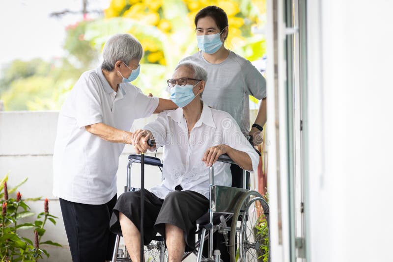 Happy asian senior woman wearing protective mask sit in wheelchair with best friend visit to the home during COVID-19,Coronavirus