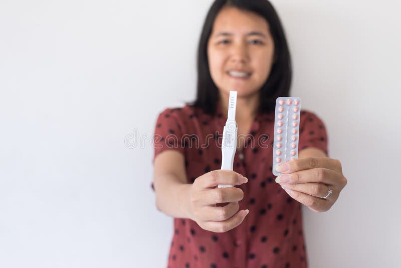 Happy asian woman hands holding birth control pill and pregnancy test,Concept for contraceptive,Copy space for text on white backg. Round stock image Happy asian woman hands holding birth control pill and pregnancy test,Concept for contraceptive,Copy space for text on white backg. Round stock image