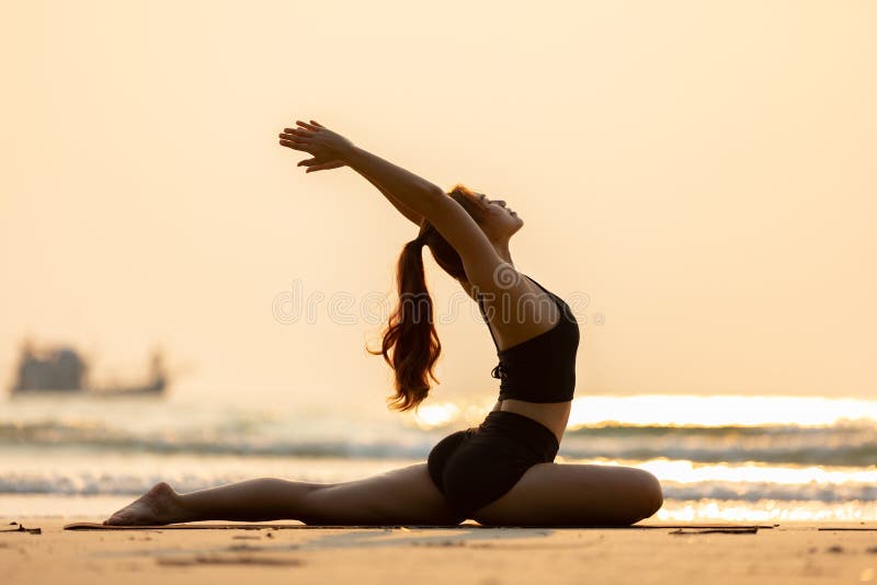 Sporty woman doing king pigeon yoga pose on the beach stock photo