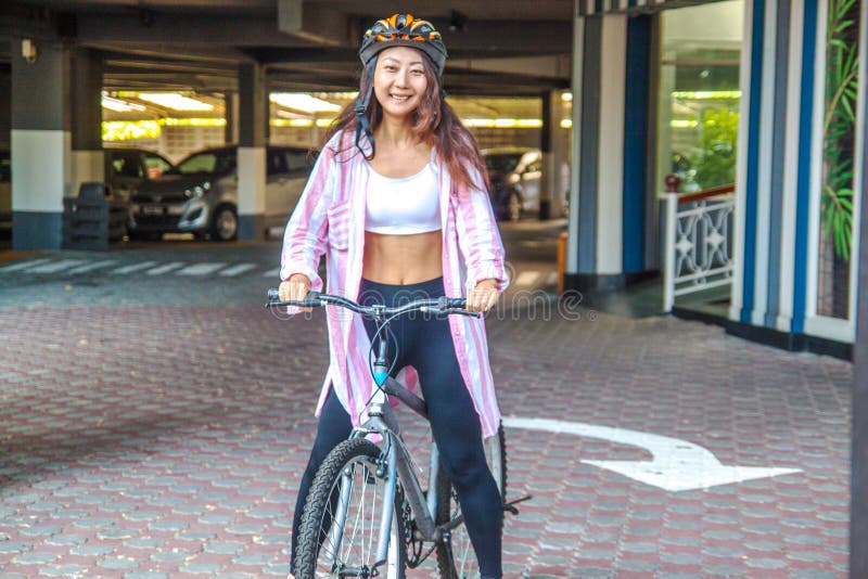 Happy woman wearing helmet riding bicycle in the summer. stock photo Happy woman wearing helmet riding bicycle in the summer. stock photo