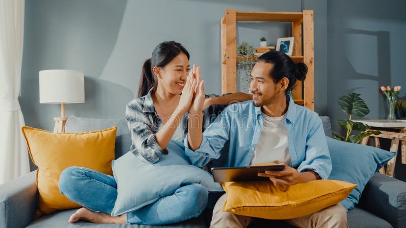 Happy Asian Young Attractive Couple Man and Woman Sit on Couch Use ...