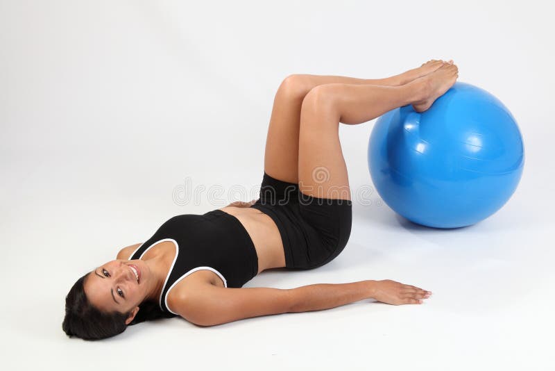 Happy athletic young woman using exercise ball
