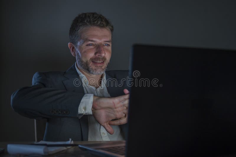 Happy and attractive businessman celebrating success in cheerful and excited face expression working late night at office laptop stock photo Happy and attractive businessman celebrating success in cheerful and excited face expression working late night at office laptop stock photo